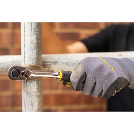 STANLEY FMMT82681-0 ratchet being used by a gloved hand on a metal pipe, close-up photography.