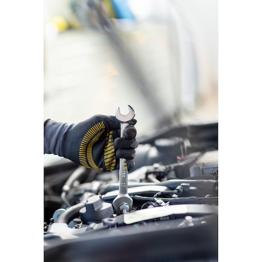 STANLEY FMMT82901-0 spanner in gloved hand tightening bolt in engine bay, close-up photography.