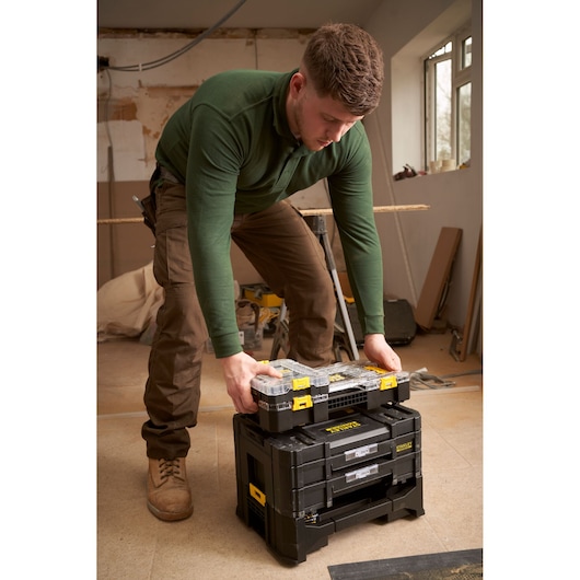 Stanley FMMT98102-0 stackable tool organizer in use on a worksite, black with yellow latches.