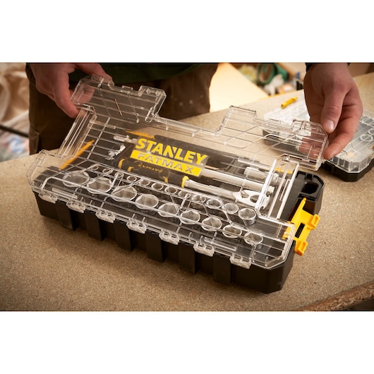 STANLEY FMMT98103-1 organizer box with clear lid and FATMAX branding, held by hands, on a workbench.