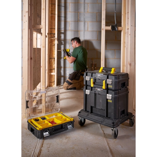 STANLEY FMST1-75502 mobile tool storage stack with yellow handles and organizer box, shown at a construction site.