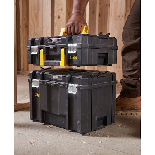 STANLEY FMST1-75502 tool box with yellow handle, shown being carried and stacked in a workshop setting.