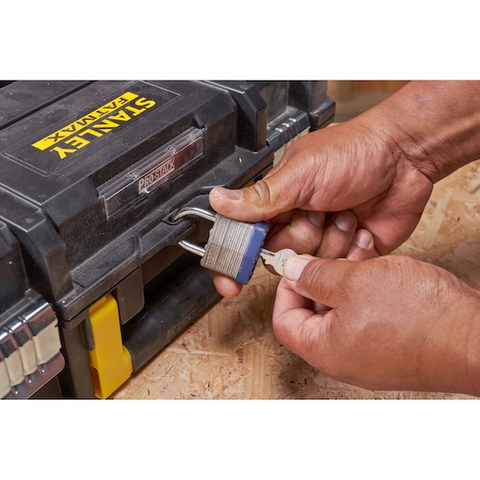 Photo of STANLEY FMST1-75502 toolbox being locked with padlock and key, close-up view.