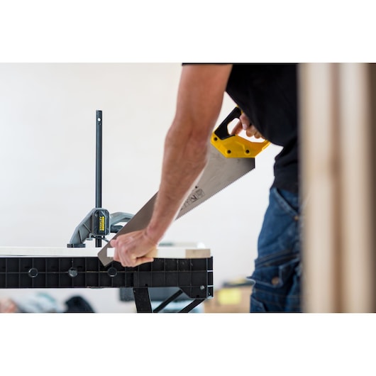 Photo of STANLEY FMST1-75672 sawhorse in use, holding wood while being cut with a hand saw.