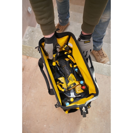 STANLEY FMST17627-1 tool bag with yellow interior filled with hand tools, shown from above on a worksite.