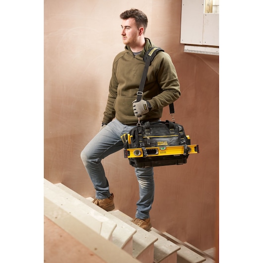 STANLEY FMST17627-1 tool bag with shoulder strap and attached tools, carried by person on stairs.