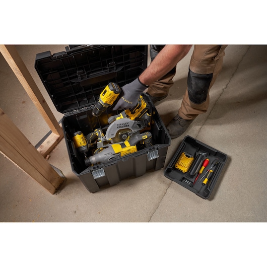 Photo of STANLEY FMST75753-9 storage box with yellow-black power tools and accessories, shown open on a workshop floor.