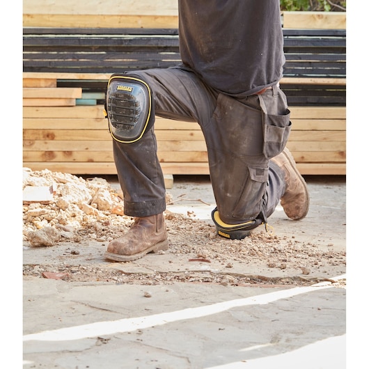 STANLEY FMST82960-1 work knee pads worn on site, black with yellow trim, durable shell design.