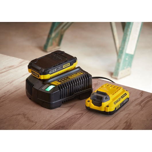 Photo of STANLEY SFMCB12D2 battery charger and battery pack in yellow and black on a wooden surface.