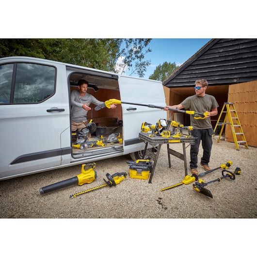 STANLEY SFMCBL7B cordless tools on display with workers near van and workbench outdoors.