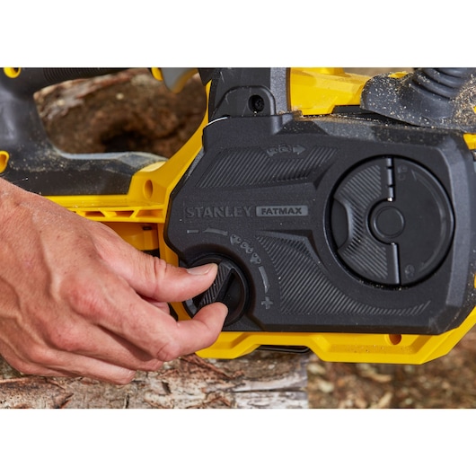 Photo of STANLEY SFMCCS630B chainsaw control panel, close-up of adjustment knob being turned.