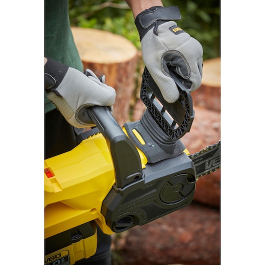 STANLEY SFMCCSB664B chainsaw close-up in use, user wearing gloves operating chain brake outdoors.