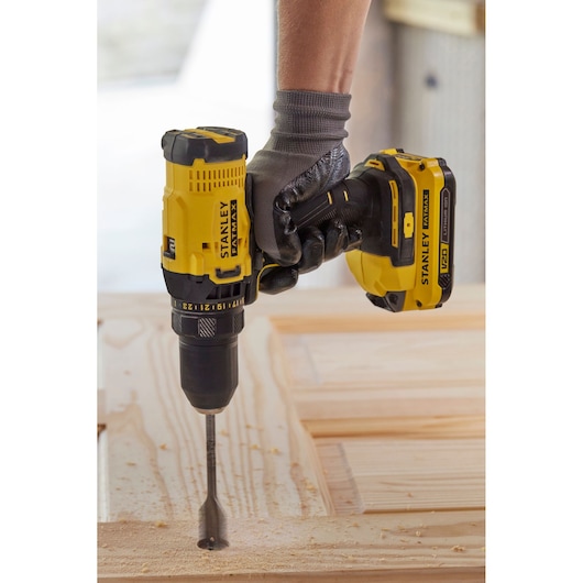 STANLEY SFMCD700C2S cordless drill in use, drilling into wood, close-up side angle.