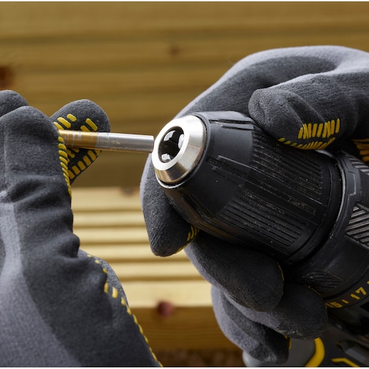 STANLEY SFMCD700C2S drill close-up with gloved hands inserting a drill bit, photography product category.