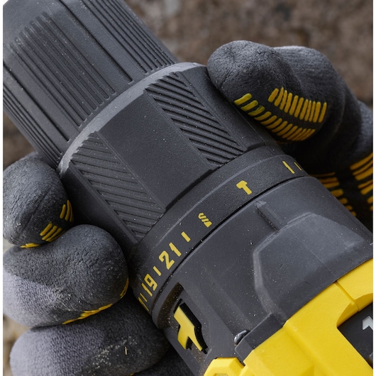 STANLEY SFMCD711C2S drill close-up, showing grip and torque adjustment with gloved hands.