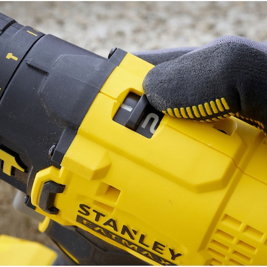 Photo of STANLEY SFMCD711C2S drill speed switch, yellow and black, with gloved hand adjusting setting.