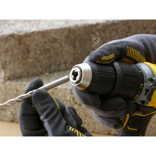 Photo of STANLEY SFMCD715D2F cordless drill with gloved hands inserting a drill bit, side view.
