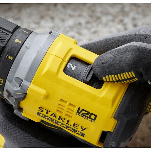 Photo of STANLEY SFMCD715D2F V20 FATMAX drill close-up with gloved hand adjusting speed switch.