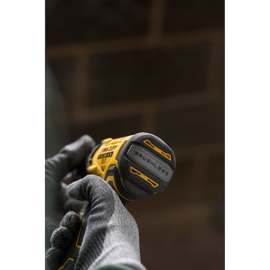 Close-up photo of STANLEY SFMCD715D2K brushless cordless drill held in gloved hands, showing the tool's base.