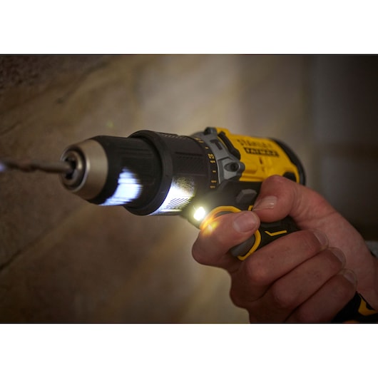 STANLEY SFMCD715D2K cordless drill with LED light in use drilling into wall, close-up angle.