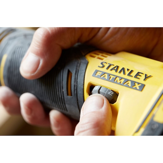 Close-up of STANLEY SFMCE500B FATMAX tool with hand adjusting speed dial, product photography.