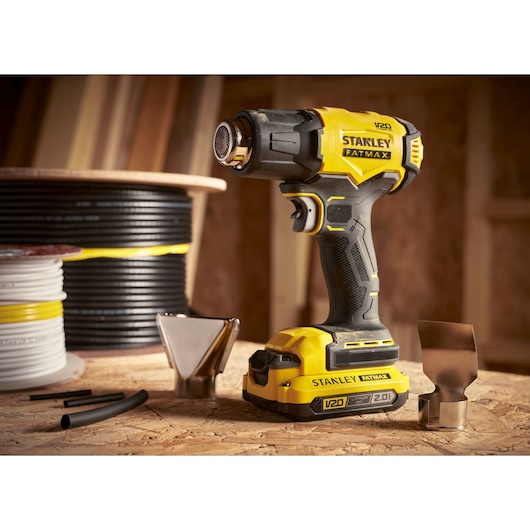 STANLEY SFMCE530B heat gun with accessories, yellow and black, photography of product on workshop table.