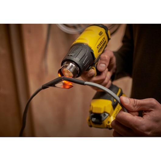 STANLEY SFMCE530B heat gun in use on a wire, close-up, photography product category.