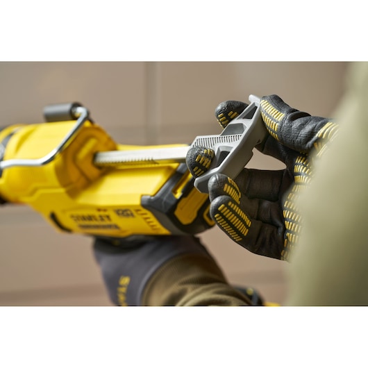 Photo of STANLEY SFMCE600B caulking gun held in gloved hands, focusing on trigger and details.