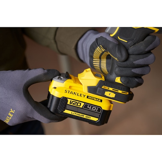Photo of STANLEY SFMCF940M1 cordless drill with V20 4.0Ah lithium-ion battery being held with gloves.