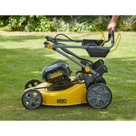 STANLEY SFMCMS2653B lawn mower side view, yellow body, foldable handle, on grass outdoors.