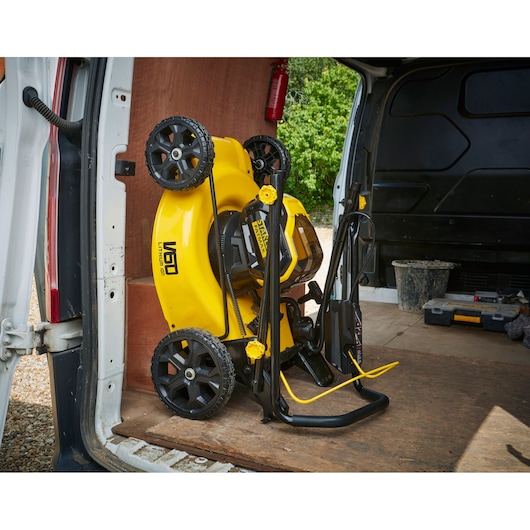 STANLEY SFMCMW2653B lawn mower folded and stored upright in a van, yellow and black design.