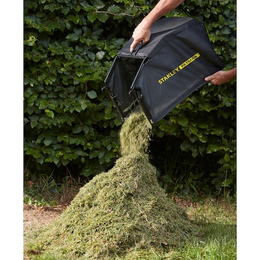 STANLEY SFMCMW2653B lawn mower grass bag emptied onto pile outdoors.
