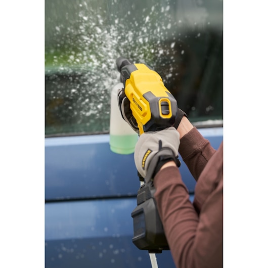 STANLEY SFMCPC93M1 pressure washer spraying water on car window, close-up showing tool in use.