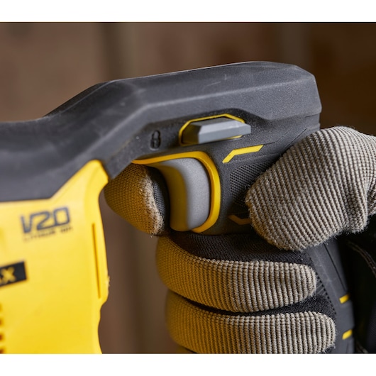 Photo of STANLEY SFMCS300B power tool handle with trigger, V20 branding, gripped by gloved hand.