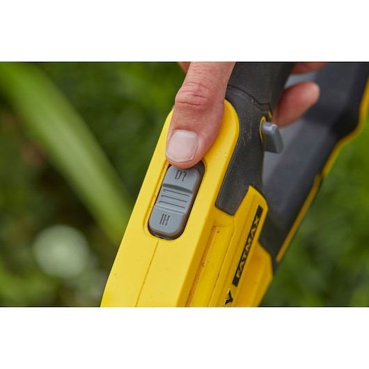 Close-up photo of STANLEY SFMCST933B power tool handle with thumb on speed control switch, yellow and black design.