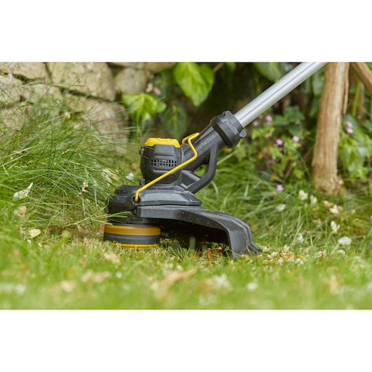STANLEY SFMCST933B string trimmer close-up in use on grass, black and yellow design.