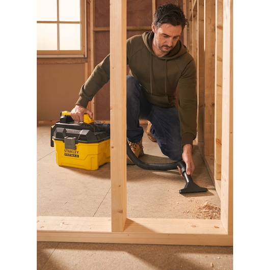 Photo of STANLEY SFMCV002B wet and dry vacuum cleaner in use, yellow and black, cleaning construction debris.
