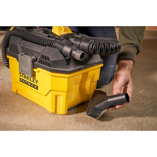 Photo of STANLEY SFMCV002B vacuum cleaner with yellow body, black hose, and accessory nozzle on floor.