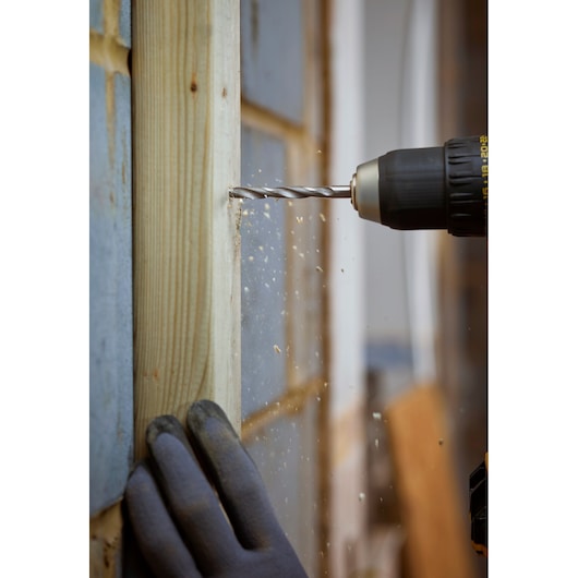 STANLEY STA88553 drill in use on wood, close-up, with gloved hand steadying the material.