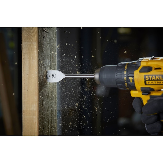 STANLEY STA88556 flat wood drill bit in action, drilling wood with shavings flying, side view, product photography