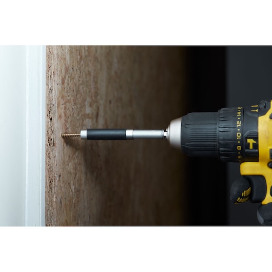 STANLEY STA88557 bit holder attached to drill driving screw into wood, close-up side view.