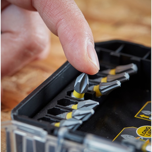STANLEY STA88560 screwdriving bit set, close-up angle, finger picking up gray and yellow bit from case.