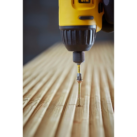 STANLEY STA88564 screwdriver bit in drill driving screw into wood, close-up angle.