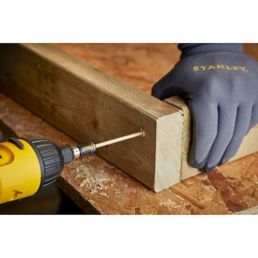 STANLEY STA88566 bit in yellow drill driving screw into wood, gloved hand holding timber.