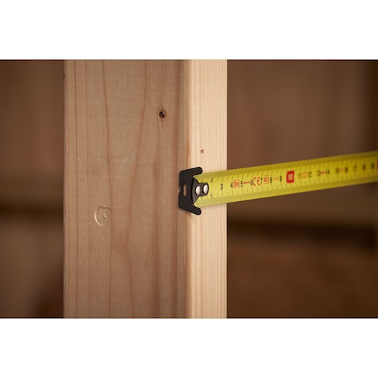 STANLEY STHT0-33559 tape measure measuring wooden beam, close-up angle.