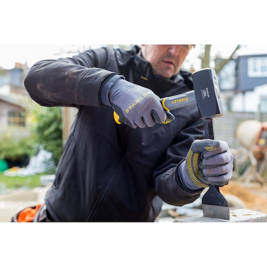 Photo of STANLEY STHT0-54128 sledgehammer in use by worker wearing gloves outdoors.