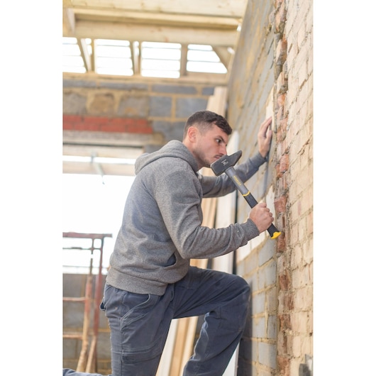 Photo of person using STANLEY STHT0-54157 sledge hammer on brick wall at a construction site.