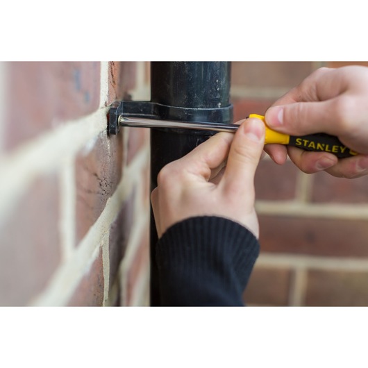 Photo of STANLEY STHT0-60308 screwdriver used on pipe bracket attached to brick wall.