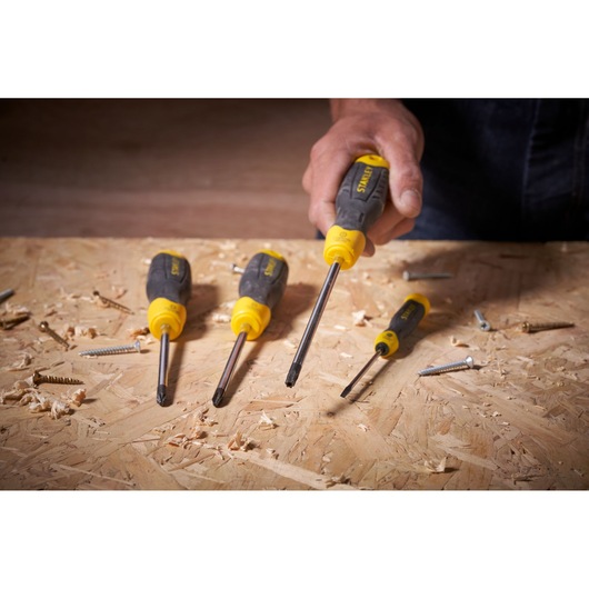 STANLEY STHT0-65153 screwdriver set with black and yellow handles on a wood surface, hand holding one tool.