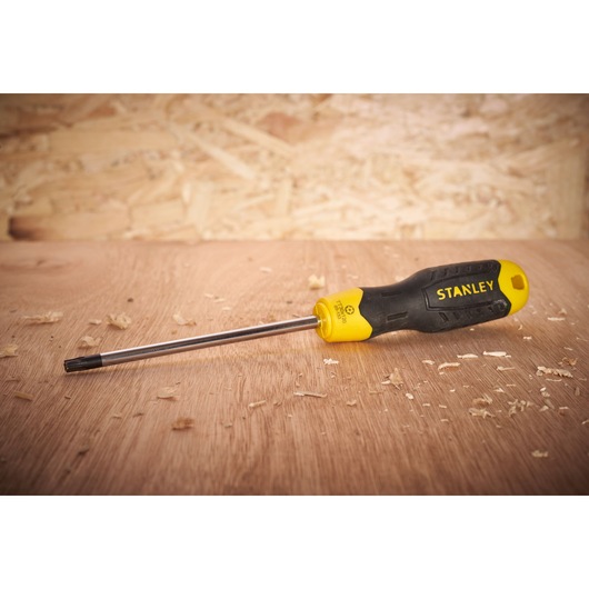 Stanley STHT0-65153 black and yellow screwdriver on wooden surface, side angle photography.